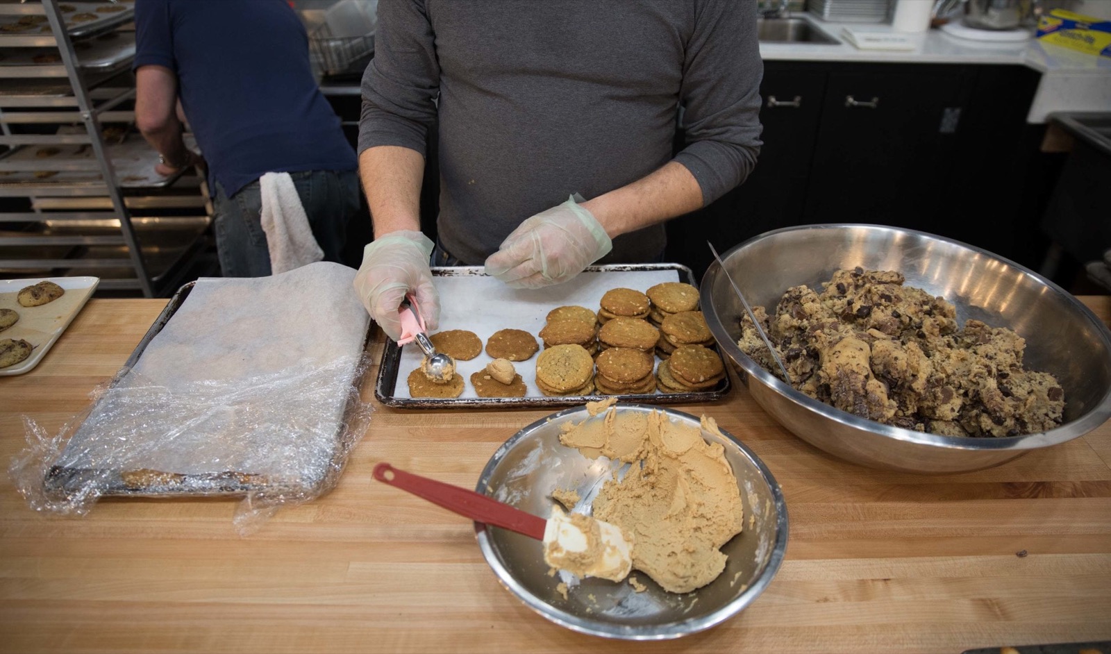 Gloved hands portioning test cookie dough at the bench between runs