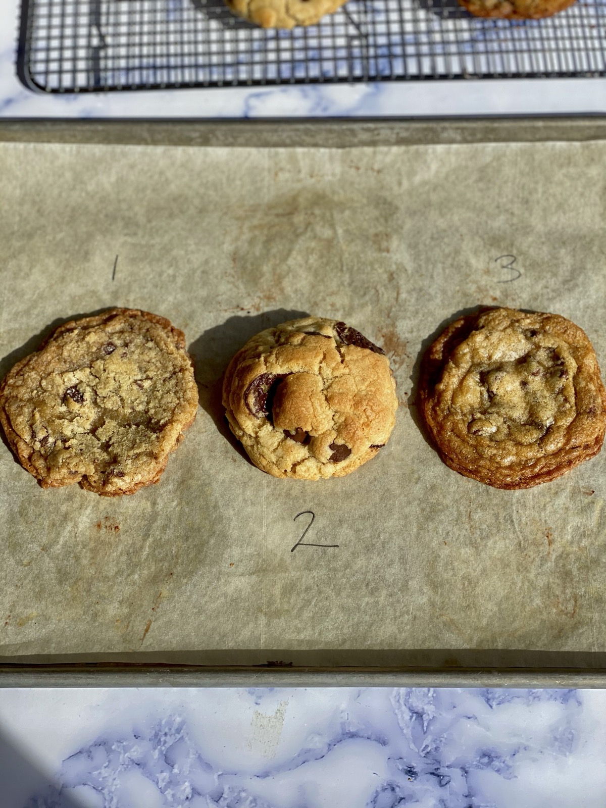 Three numbered test cookie variations side by side on a parchment-lined tray